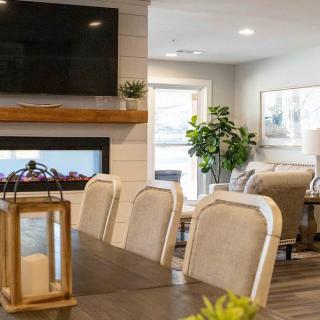 A cozy living room with a dining area, featuring a fireplace and modern furnishings.