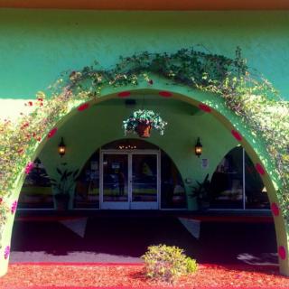 A vibrant building entrance with an arched design, adorned with vines and greenery.