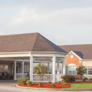 A building with a covered entrance and well-maintained landscaping on a clear day.