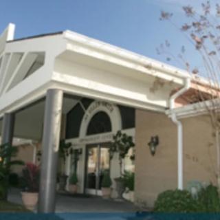A view of a building entrance featuring columns and surrounding greenery under a clear sky.