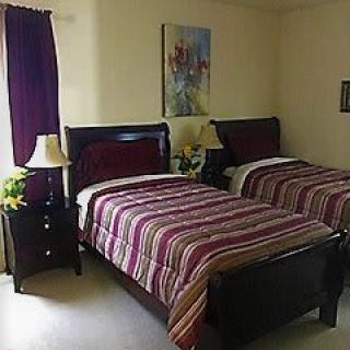 A cozy bedroom with twin beds featuring striped bedding and a nightstand with a lamp.