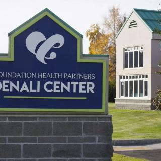 Sign at the entrance of Foundation Health Partners Denali Center with a building in the background.