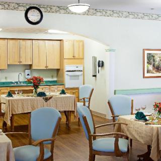 A cozy dining area with tables and chairs, adjacent to a kitchen space.