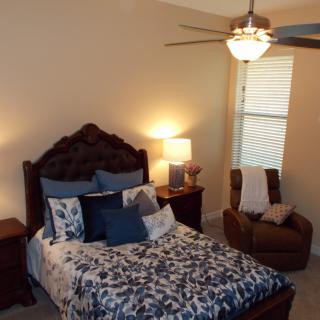 A cozy bedroom with a well-decorated bed and an armchair in the corner.