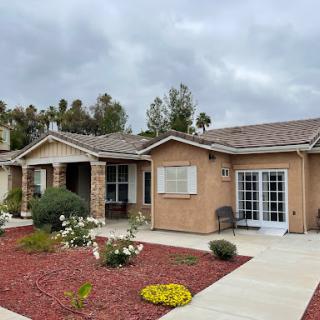 A charming residential home featuring a landscaped garden under a cloudy sky.