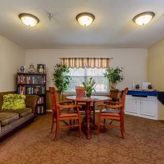 A cozy living room with a round table, chairs, a sofa, and a bookshelf filled with books.
