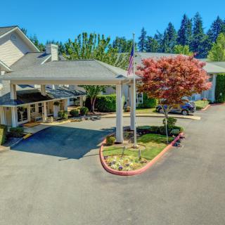A building entrance with a covered driveway surrounded by trees and landscaping.