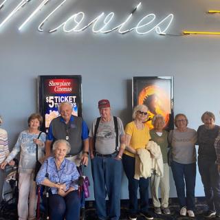 A group of people standing together in front of movie posters at a theater.