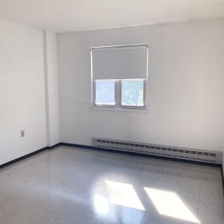 A bright, empty room with white walls and a window letting in natural light.