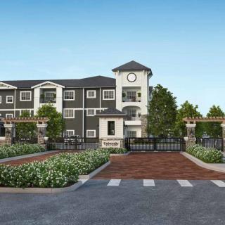 A modern apartment complex with a central clock tower and landscaped entrance.