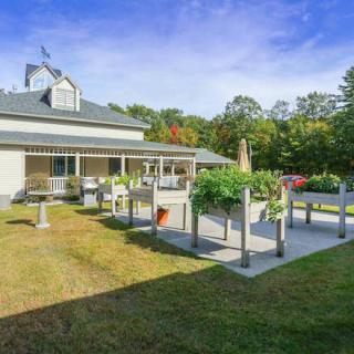 A beautiful house with an inviting patio and lush garden on a sunny day.
