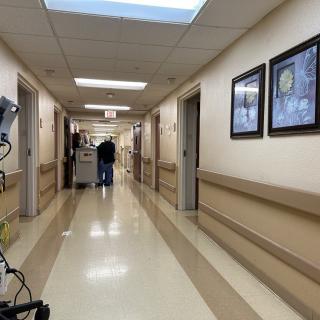 A hospital hallway with medical equipment and framed pictures on the walls.