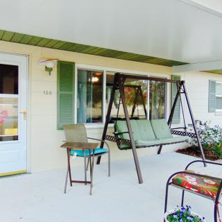 A cozy outdoor patio area with a swing, chairs, and a small table.