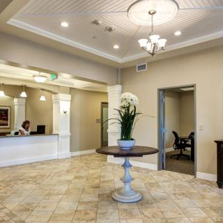 A modern office lobby with a reception desk and a central table adorned with flowers.