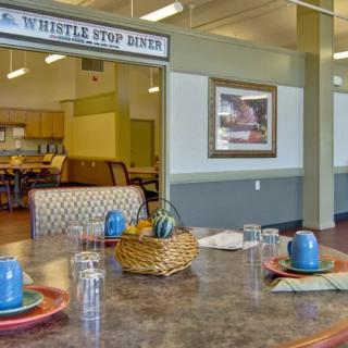 A cozy diner with a neatly set table and a view into the kitchen area.