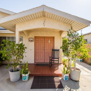 A welcoming porch with a rocking chair and potted plants at the entrance of a house.