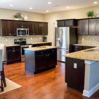 A modern kitchen featuring dark oak cabinets, granite countertops, and stainless steel appliances in an open layout.
