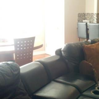A cozy living room featuring a dark sofa and adjacent dining area.