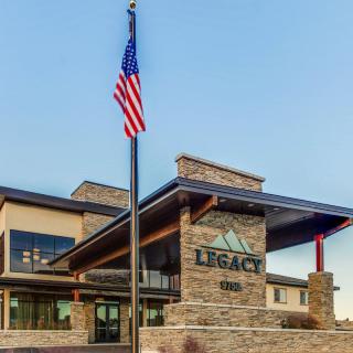 A modern building with a stone facade and an American flag in front, labeled 'Legacy'.