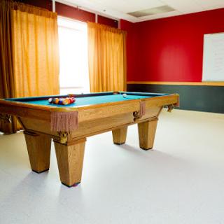 A spacious game room featuring a wooden pool table and vibrant red walls.