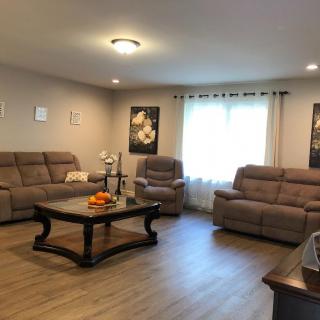 A cozy living room featuring comfortable sofas and a stylish coffee table, complemented by wall art and natural light from the window.