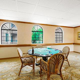 A tranquil room featuring a round table with wicker chairs and large windows, inviting natural light.