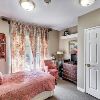 A cozy bedroom with floral curtains, a bed, and a dresser.