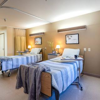 A view of a hospital patient room featuring two twin beds and a warm, inviting atmosphere.