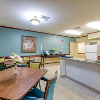 A cozy dining area with a kitchen, featuring colorful chairs and a wooden table.