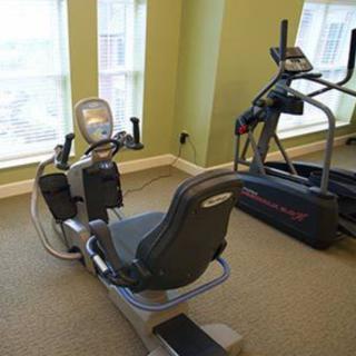 A gym room featuring a recumbent bike and an elliptical machine by the window.