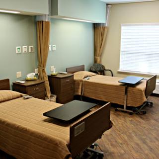 A view of a patient room in a hospital, featuring two beds and essential medical furnishings.