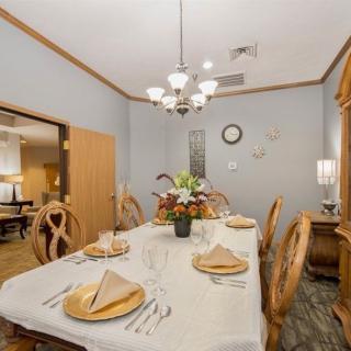 A neatly set dining room with a chandelier and decorative elements.