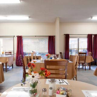 An empty dining room with neatly arranged tables and chairs, adorned with floral decorations.