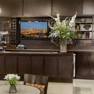 A modern lobby with a sleek reception desk, a large floral arrangement, and a television mounted on the wall.
