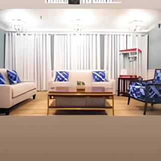 A modern living room with stylish furniture, featuring a sofa and armchair accented with blue pillows, and a popcorn machine in the corner.