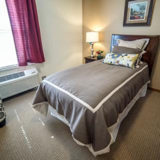 A small, cozy bedroom with a single bed and a lamp beside it.