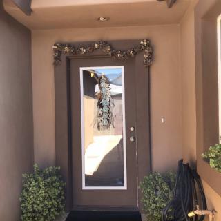 A welcoming entrance with decorative foliage and a reflective glass door.