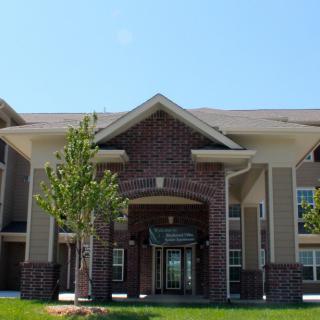 A modern apartment building with a central entrance and landscaped surroundings.