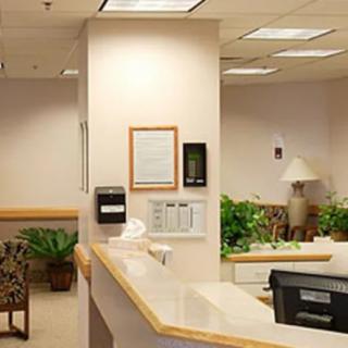 A reception area with a front desk, seating, and indoor plants.