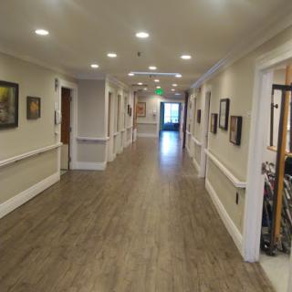 A well-lit hallway featuring wooden flooring and artworks on the walls.