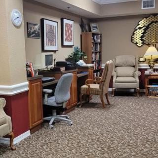An office space featuring desks, chairs, a computer, and decorative wall art.