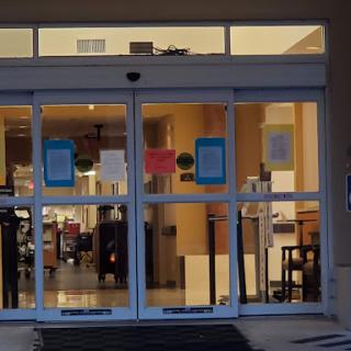 The entrance to a building showcasing glass doors and visible interior furniture.