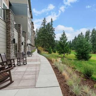 A scenic outdoor patio area with rocking chairs along a building, overlooking a lush green landscape.