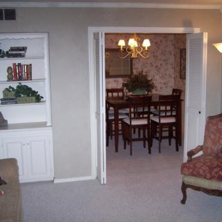 A cozy living room with a view into a dining area featuring a chandelier and a set of chairs around a dining table.