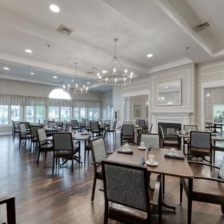 An elegant and spacious dining room with chandeliers, neatly arranged tables, and comfortable seating.