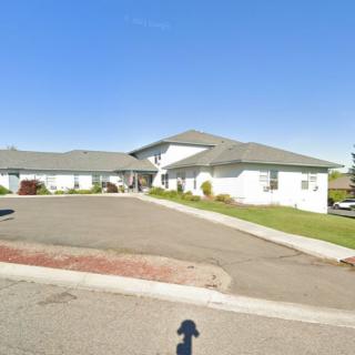 A suburban residential building with a driveway and landscaped surroundings.