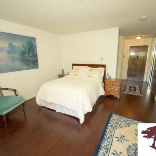 A cozy bedroom featuring a bed with white linens, wooden furniture, and a painting on the wall.