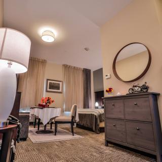 Cozy bedroom interior featuring a dining table, chairs, lamp, and mirror.