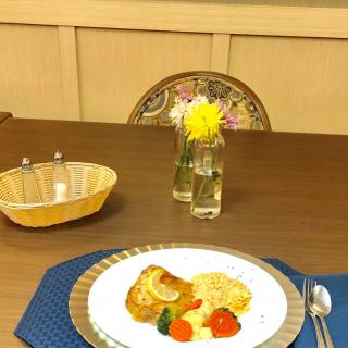 A beautifully set dining table with a plated meal and a vase of flowers.