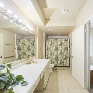 A spacious bathroom with a large mirror, dual sinks, and a floral shower curtain.